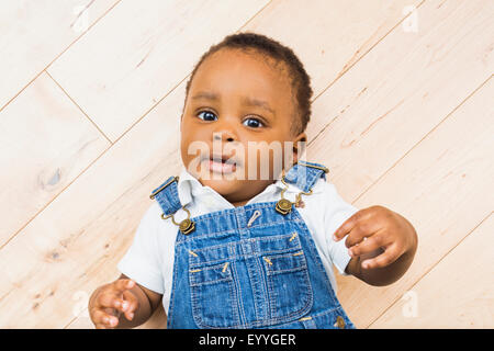 Black baby boy posa sul pavimento Foto Stock