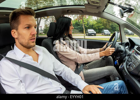 Giovane donna alla guida di auto con sottolineato l uomo come co-driver, Austria Foto Stock