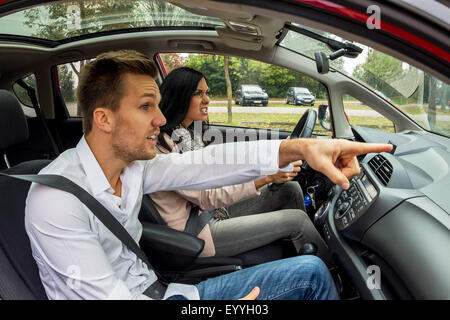 Giovane donna alla guida di auto con gesticulating uomo come co-driver, Austria Foto Stock