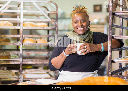 Baker nero di bere il caffè in cucina da forno Foto Stock