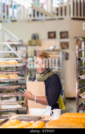 Baker nero azienda appunti in cucina da forno Foto Stock