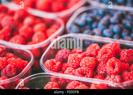 Assortimento di organico fresco Ribes Lamponi Mirtilli e a produrre il mercato locale in cesti e contenitori. Foto Stock