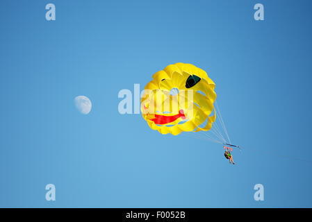 Un paracadute trainato in mare con un cielo blu chiaro in background. Luna sulla sinistra. Foto Stock