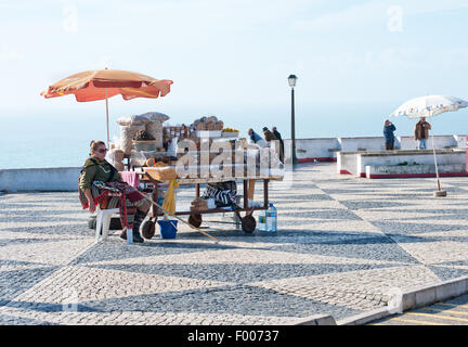 Una donna vende frutta secca ed essiccata nella piazza di città vecchia Nazare (Sítio), Portogallo Foto Stock