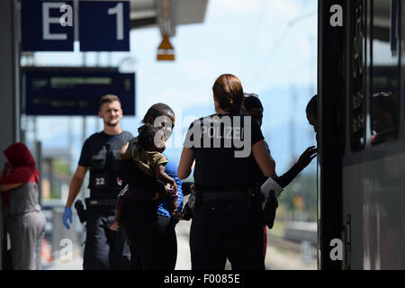 Rosenheim, Germania. 04 Ago, 2015. Una donna che porta un bambino parla a un funzionario di polizia su una piattaforma presso la stazione ferroviaria di Rosenheim, Germania, 04 agosto 2015. La polizia tedesca prelevati circa 150 rifugiati provenienti da vari paesi in un treno in arrivo da Verona. Dopo aver cercato e registrati hanno ricevuto un documento di identificazione presso un ufficio del tedesco della polizia federale e sono stati inviati al rifugiato struttura di accoglienza di Monaco dove essi possono chiedere asilo. Foto: ANDREAS GEBERT/dpa/Alamy Live News Foto Stock