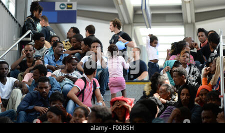 Rosenheim, Germania. 04 Ago, 2015. Un gruppo di rifugiati provenienti da vari paesi in attesa di essere registrati si siede su una rampa di scale alla stazione ferroviaria in Rosenheim, Germania, 04 agosto 2015. La polizia tedesca prelevati circa 150 rifugiati provenienti da vari paesi in un treno in arrivo da Verona. Dopo aver cercato e registrati hanno ricevuto un documento di identificazione presso un ufficio del tedesco della polizia federale e sono stati inviati al rifugiato struttura di accoglienza di Monaco dove essi possono chiedere asilo. Foto: ANDREAS GEBERT/dpa/Alamy Live News Foto Stock