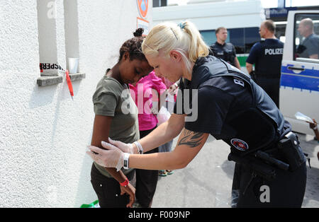 Rosenheim, Germania. 04 Ago, 2015. Ruth dall Eritrea è frisked dal funzionario di polizia Sandra Mitschker presso la stazione ferroviaria di Rosenheim, Germania, 04 agosto 2015. La polizia tedesca prelevati circa 150 rifugiati provenienti da vari paesi in un treno in arrivo da Verona. Dopo aver cercato e registrati hanno ricevuto un documento di identificazione presso un ufficio del tedesco della polizia federale e sono stati inviati al rifugiato struttura di accoglienza di Monaco dove essi possono chiedere asilo. Foto: ANDREAS GEBERT/dpa/Alamy Live News Foto Stock