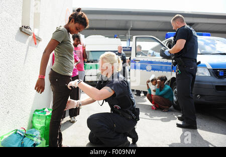 Rosenheim, Germania. 04 Ago, 2015. Ruth dall Eritrea è frisked dal funzionario di polizia Sandra Mitschker presso la stazione ferroviaria di Rosenheim, Germania, 04 agosto 2015. La polizia tedesca prelevati circa 150 rifugiati provenienti da vari paesi in un treno in arrivo da Verona. Dopo aver cercato e registrati hanno ricevuto un documento di identificazione presso un ufficio del tedesco della polizia federale e sono stati inviati al rifugiato struttura di accoglienza di Monaco dove essi possono chiedere asilo. Foto: ANDREAS GEBERT/dpa/Alamy Live News Foto Stock