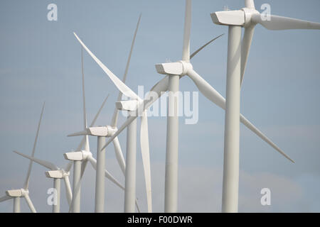 In prossimità di diverse turbine eoliche in una riga con un cielo blu chiaro Foto Stock