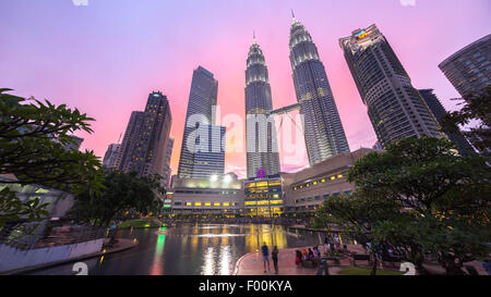 Fontana al Suria KLCC con Petronas torri e palazzi di uffici a Blue ora tramonto di notte. Foto Stock