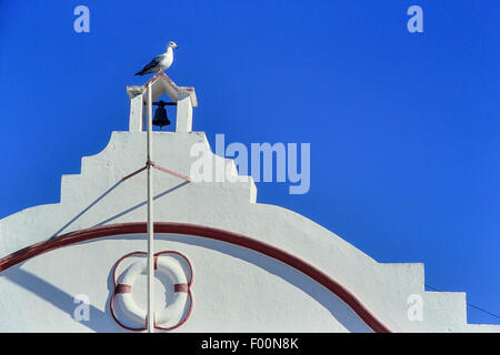 Seagull appollaiato sulla torre campanaria di Alvor scialuppa di salvataggio stazione. Algarve. Il Portogallo. Foto Stock