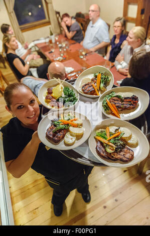 Cameriera che trasportano le cinque piastre di cibo a diners presso il ristorante artesiano, Ojo Caliente sorgenti minerali Resort & Spa. Stati Uniti d'America Foto Stock