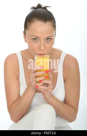 Giovane donna con in mano un bicchiere di rinfrescante salutare spremuta di arancia fresca per colazione isolata contro uno sfondo bianco con spazio di copia Foto Stock