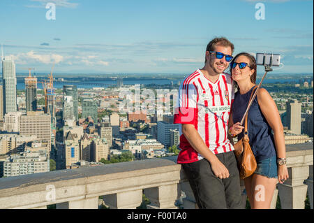 Coppia giovane usando un bastone selfie nella parte anteriore della Skyline di Montreal, Kondiaronk belvedere. Foto Stock