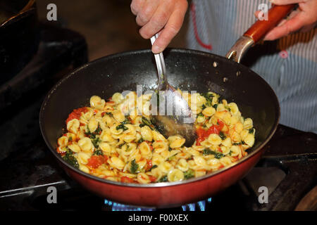 Una donna locale prepara le orecchiette a livello locale un piatto di pasta, ad una cucina esterna in Bari vecchia trimestre di Bari, Italia. Foto Stock