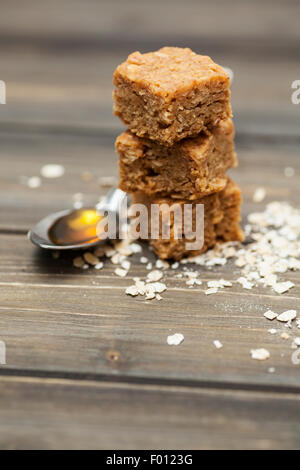 Pila di fragrante e indulgente flapjacks su uno sfondo di legno circondato da ingredienti Foto Stock