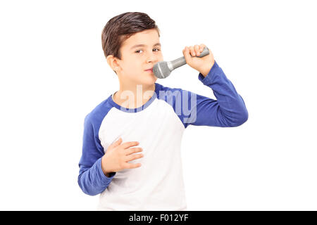 Gioiosa ragazzino cantando su un microfono isolati su sfondo bianco Foto Stock