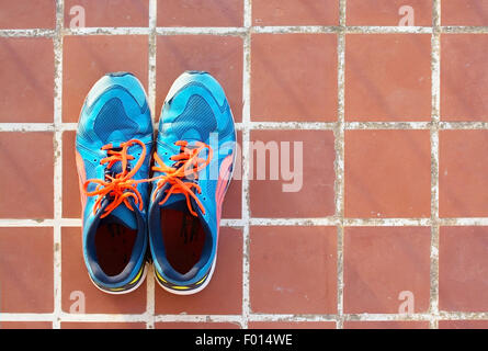 Blu scarpe sportive sul pavimento in terracotta piastrella quadrata texture di sfondo. Foto Stock