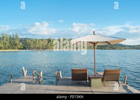 Estate, Viaggi, vacanze e concetto di vacanza - sedie a sdraio e ombrellone sulla scrivania di legno contro il cielo blu in Phuket, Tailandia Foto Stock