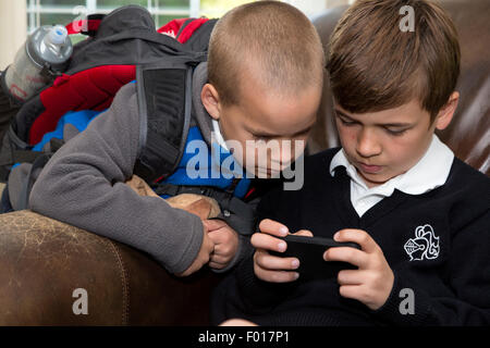 Fratello più giovane età (7) Guardando il fratello maggiore età (9) Utilizza il suo iPod. Signor Foto Stock