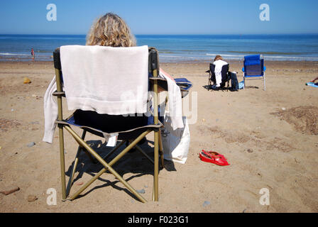 Donna rilassante in una sedia in riva al mare su di una spiaggia di sabbia Foto Stock