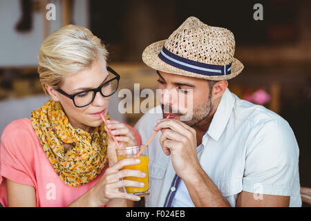 Carino coppia su una data la condivisione di un succo di arancia Foto Stock