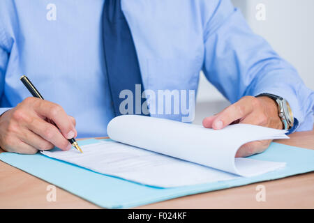 Imprenditore sorridente la lettura di un contrat prima della firma di esso Foto Stock