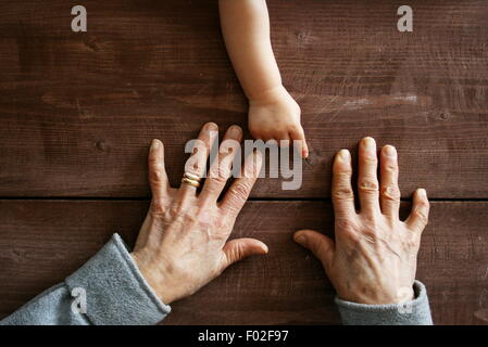 Baby boy la mano puntando alla nonna mani Foto Stock