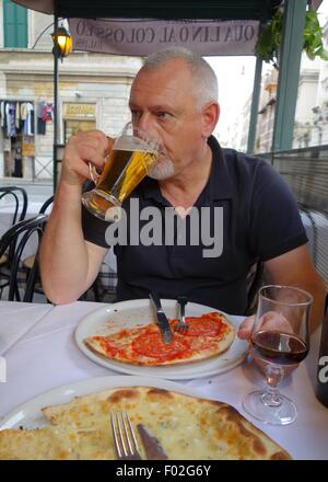 Uomo di bere birra in corrispondenza di un bordo strada cafe a Roma, Italia, Europa Foto Stock