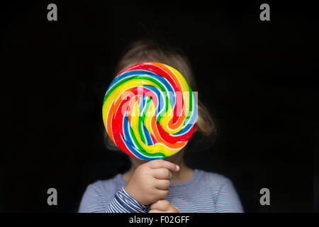 Ritratto di una ragazza che tiene un lollipop multicolore Foto Stock