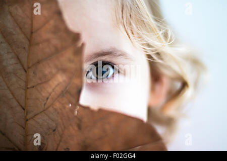 Ritratto di una bambina che si nasconde dietro la foglia Foto Stock