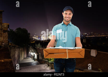 Immagine composita del corriere bello uomo con pacco Foto Stock