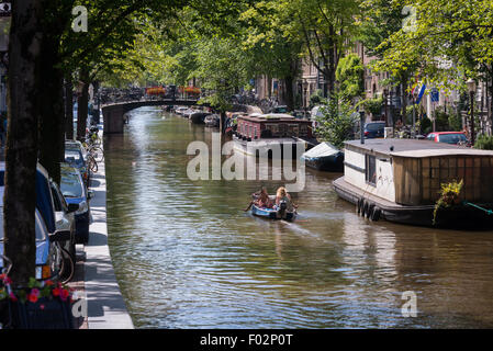 Amsterdam canal e case galleggianti crogiolarvi al sole estivo Foto Stock