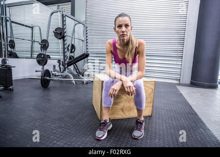 Muscolari gravi donna seduta su una scatola di legno Foto Stock