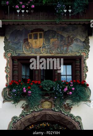 Stagecoach con cavalli, affresco dipinto al di sopra di una finestra con fioriere, facciata del Gasthof Post Hotel in Kossen, Tirolo, Austria. Foto Stock