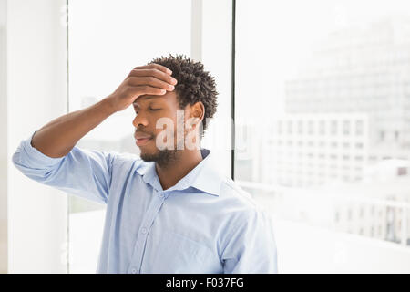 Giovane imprenditore di concentrazione appoggiata con la schiena contro una finestra Foto Stock
