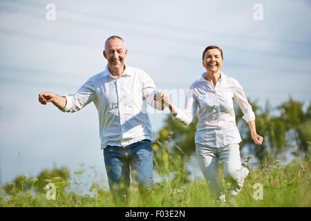 Felice coppia senior in esecuzione su prato in estate Foto Stock