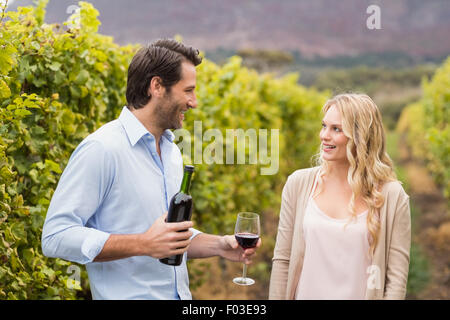 Giovane uomo felice che offre il vino a una giovane donna Foto Stock