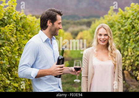 Giovane uomo felice che offre il vino a una giovane donna Foto Stock