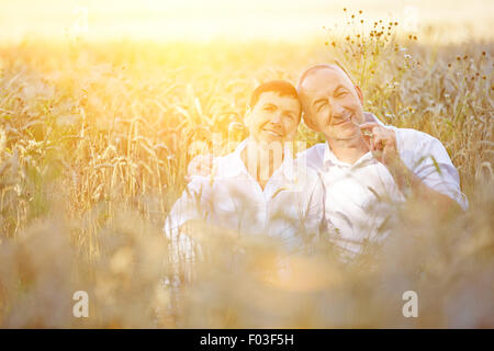Due vecchi contadini seduti nel campo di grano in un estate Foto Stock