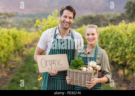 Due giovani felici gli agricoltori tenendo un segno e un cesto di verdure Foto Stock