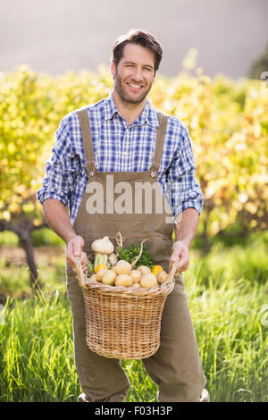Sorridendo l'agricoltore che detiene un cesto di patate Foto Stock