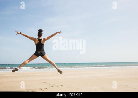 Montare la donna salta sulla sabbia Foto Stock