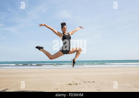 Montare la donna salta sulla sabbia Foto Stock