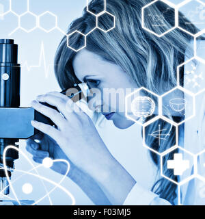 Immagine composita della bionda attraente scienziato guardando attraverso un microscopio Foto Stock