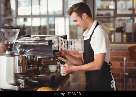 Sorridente barista latte di cottura a vapore in macchina da caffè Foto Stock