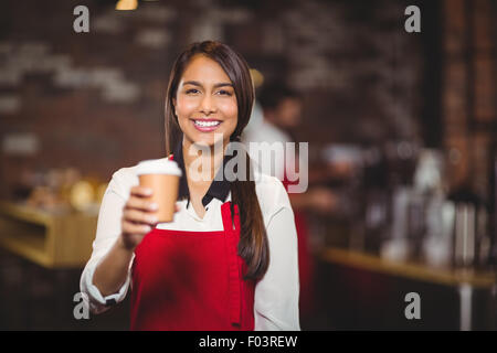 Sorridente cameriera di consegnare un take-away mug Foto Stock