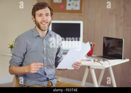 Barbuto hipster sorridente in telecamera tenendo note Foto Stock