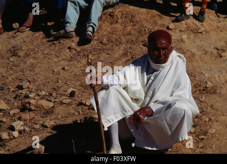 Uomo in abiti tradizionali seduto a terra, Matmata festival berbero, Tunisia. Foto Stock