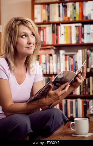 Donna con lettura a home Foto Stock